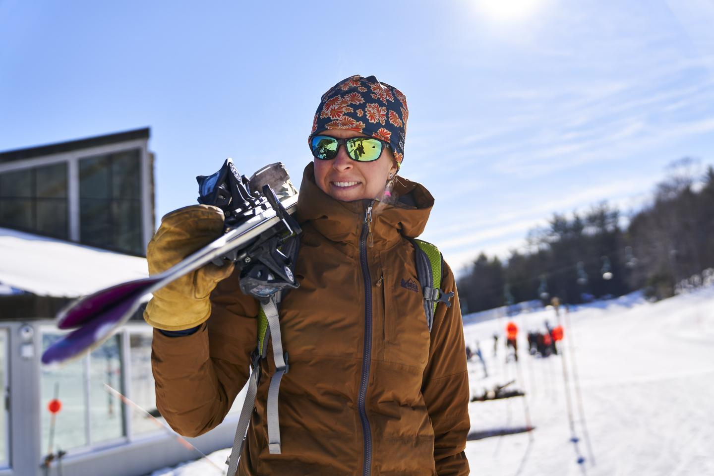 Woman carrying skis on her shoulder at Saskadena Six