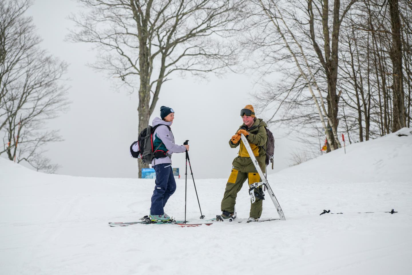 Two people with ski gear converse on a snowy slope.