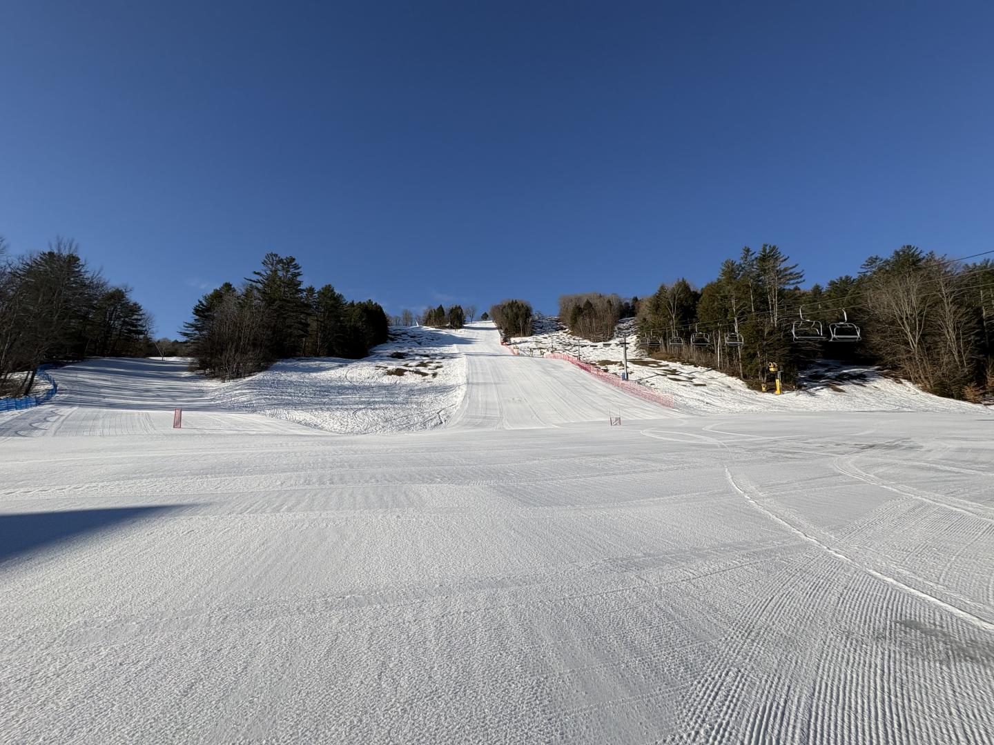 Snow-covered ski slope under a clear blue sky.