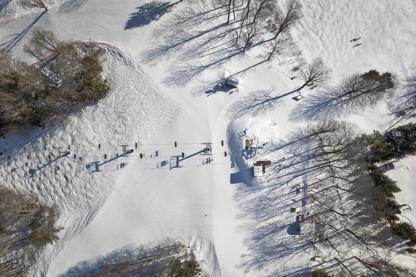Snow-covered landscape with small figures casting long shadows.
